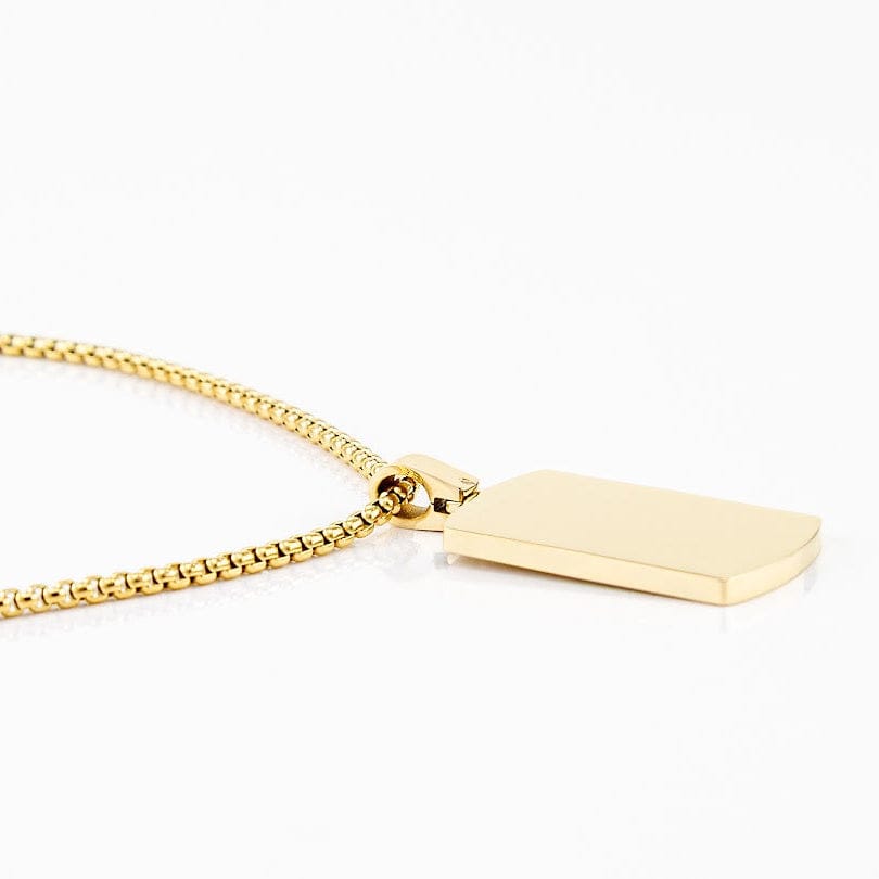 Gold dog tag urn pendant on a white background, side view