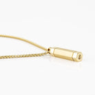 Gold plated cylinder urn necklace on a white background